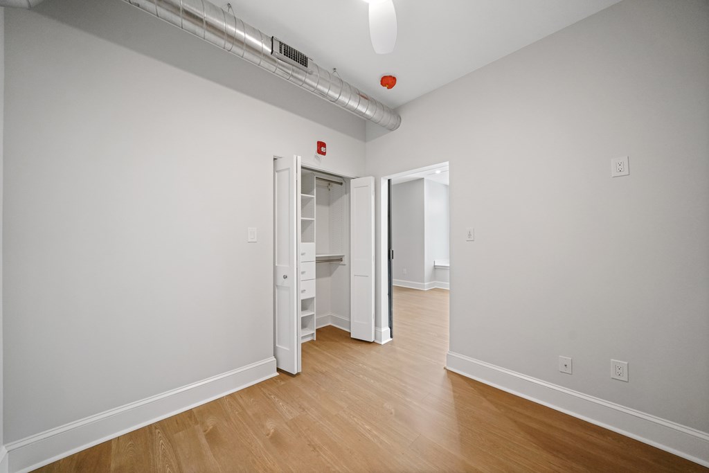 a room with white walls and wood floors and an open closet